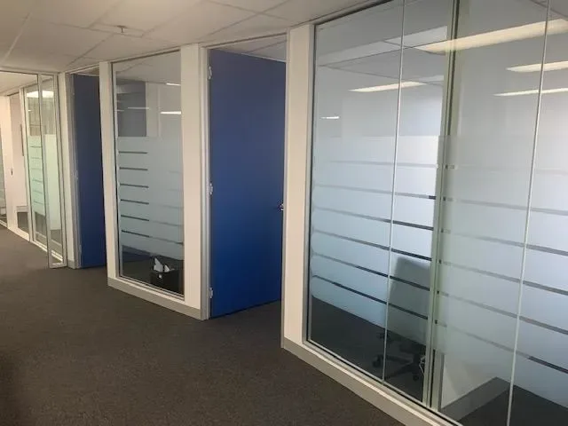 Corridor of glass-fronted private offices with frosted privacy strips
